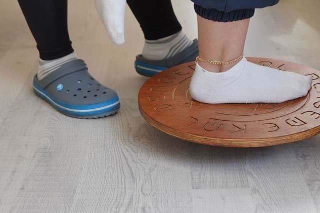 Patient performing single-leg balance training on a wobble board during rehabilitation